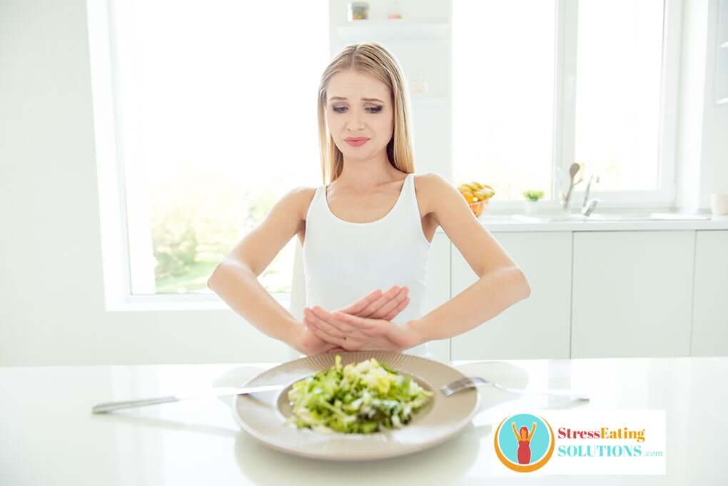 very thin woman who has a disordered eating condition pushing her to eat less pushing away her salad
